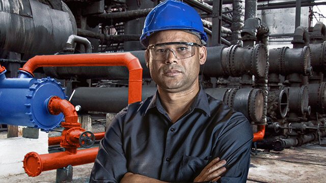 Man wearing hard hat and safety glasses with crossed arms infront of an installed Alfa Laval welded spiral heat exchanger.